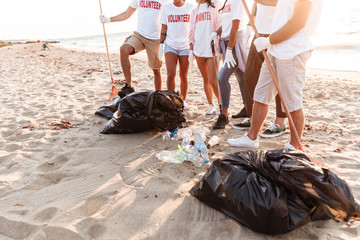 Group of young friends volunteers cleaning beach