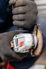 A man works with an angle grinder. Cuts metal.