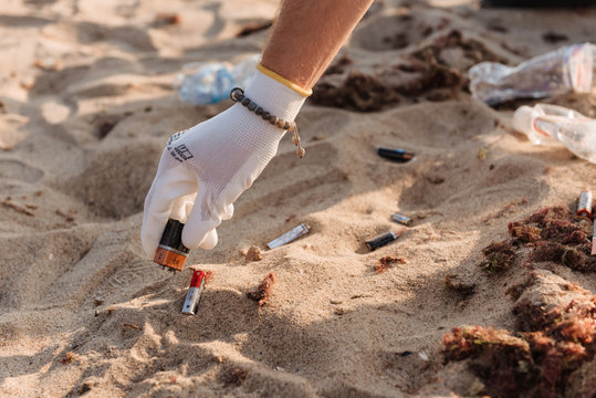 Cropped image of eco volunteer cleaning beach from toxic batteries