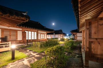 Obraz premium Architecture traditional wooden house illumination with the moon in blue sky at Ojuk Hanok Village