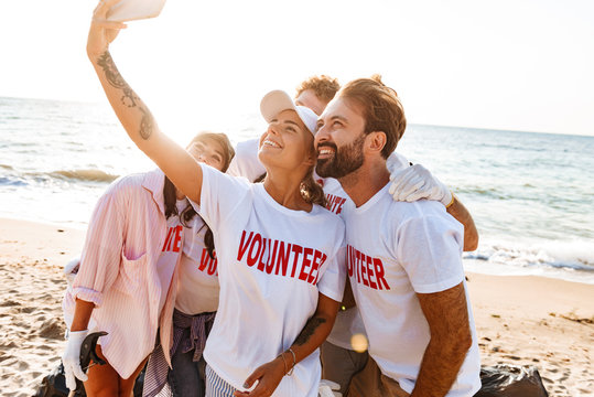 Image of smiling attractive volunteers taking selfie photo on cellphone