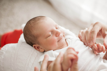 Cute newborn baby sleeping in mother's arms. Motherhood.