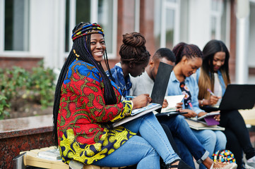 Group of five african college students spending time together on campus at university yard. Black...