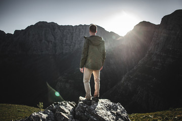 Young man watches the sun rise on a mountain top
