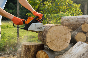  Chainsaw that stands on a heap of firewood in the yard on a beautiful background of green grass...