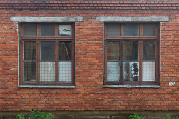 Two old broken brown wooden windows with metal lattices on dirty red brick wall background