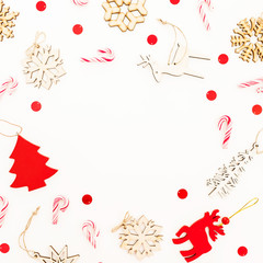 Christmas frame with wooden decoration, snowflakes and candy canes on white. Flat lay