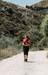 Naklejka na ściany i meble Active girl running at mountain, rural way