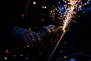 Sparks from metal sawing. A man is cutting a metal profile with a grinder. Work in the garage....