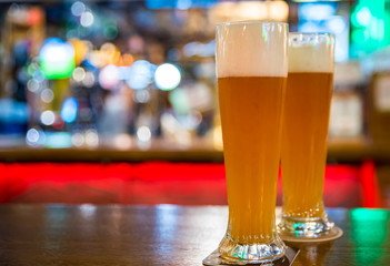 two glass of light beer stands on a table in a bar or pub