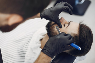 Man with a beard. Hairdresser with a client. Brunette in a barbershop