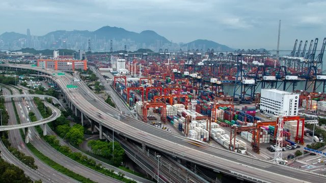 Timelapse modern Hong Kong harbour with large busy container terminal and various cranes near city overpass multi-level highways zoom out