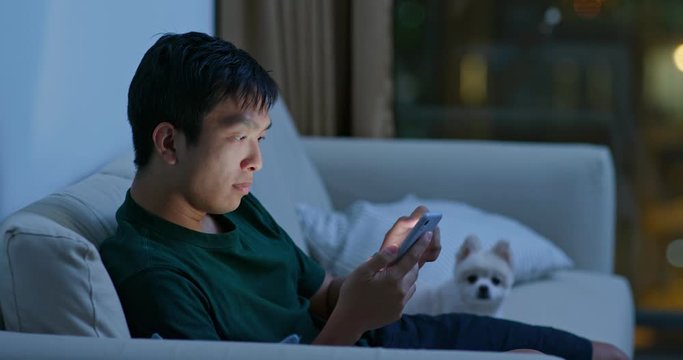 Man use of mobile phone with his pomeranian dog