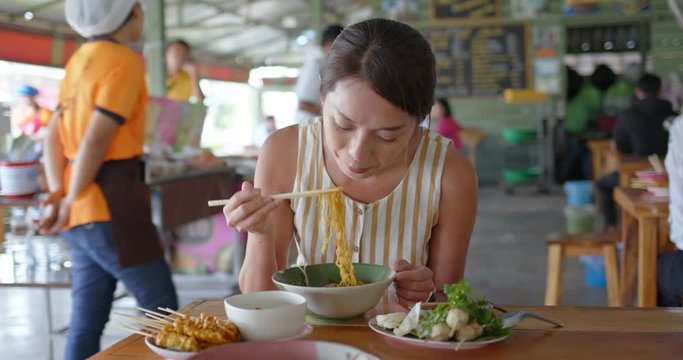 Woman eat boat noodles at outdoor street vendor in Thailand