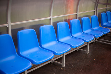 Fototapeta premium A row of blue chairs in a stadium. A place for a trainer. Armchairs where the team sits.
