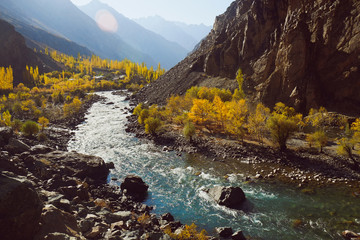 Beautiful nature landscape view of winding river flowing along valley in Hindu Kush mountain range. Autumn season in Gupis Ghizer, Gilgit Baltistan, Pakistan.