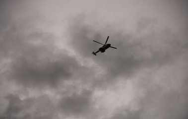 Fototapeta na wymiar Helicopter flying over a gray sky