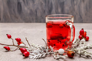 Hot dog-rose tea. Winter drink for good mood with fresh berries, leaves and candies. Stone concrete...