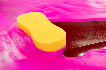 Concept car wash of female. Yellow sponge lies on pink foam clean dirt