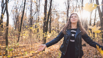 Beautiful woman posing standing in autumn forest. Girl in leather black jacket walking in the forest