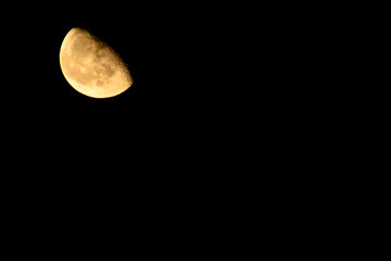 Orange half moon in the dark night sky