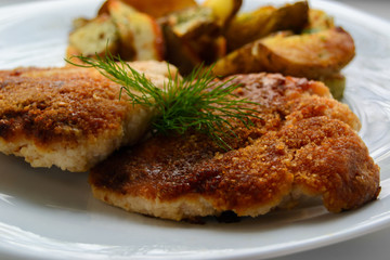 Schnitzel with wedges patoto on white background.  Close up