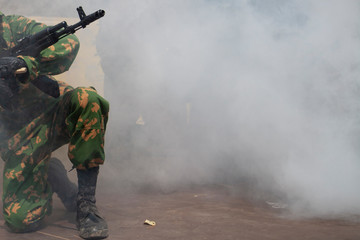 Naklejka premium The soldier is preparing to attack. The smoke of war and the military awaits directions. Machine gun barrel at war. Demonstration performance of the military.