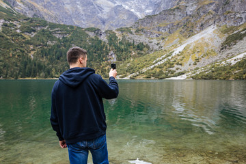 Tourist with action camera in hand. Tatra National Park, Poland. Small Mountains Lake 'Morskie Oko' In  Morning.