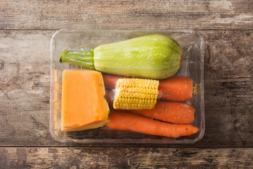 Various vegetables packaged plastic on wooden table