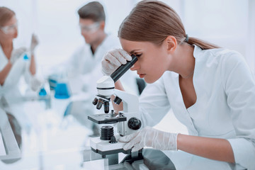 female scientist using a microscope in a chemical laboratory - obrazy, fototapety, plakaty
