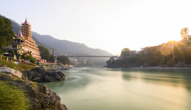 Stunning view of the Ganga river embankment with the Lakshman Jhula bridge and Tera Manzil Temple (Trimbakeshwar) during a beautiful sunset. Rishikesh, Uttarakhand, India.
