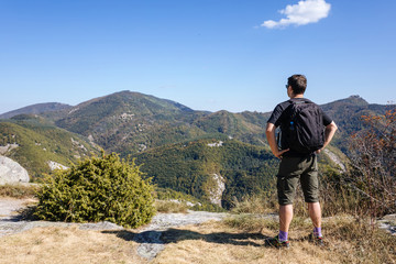 Fototapeta premium Relaxed tourist admiring the view from the mountain top,hiking concept, Panoramic view landscape from mountain, Bulgaria