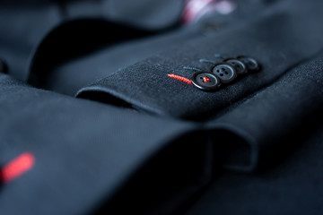 Close up of The black buttons are lined up on the sleeves of the black suit.