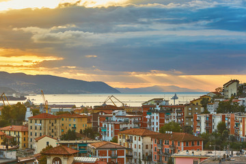 Dramatic sky with clouds and sun beams during sunrise in La Spezia