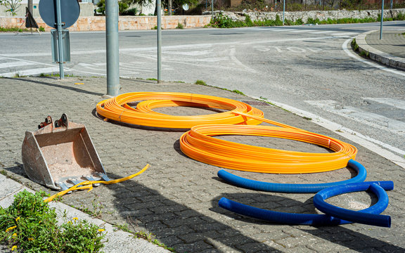 Rolls of fiber optic cable ducts resting on the pavement waiting to be buried