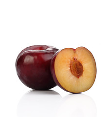 Plum with a slice and leaf on a white background.