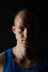 Portrait of serious young man in blue shirt looking at camera isolated on black background