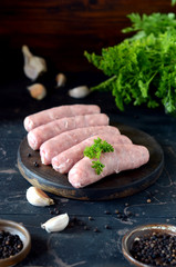Raw homemade sausages on a wooden cutting board on a dark wooden background