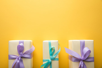 flat lay with gift boxes with violet and blue ribbons on yellow background with copy space