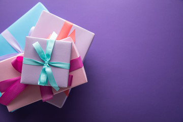 top view of colorful gift boxes with ribbons and bows on purple background with copy space