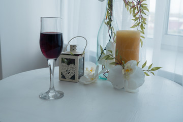 Background. A glass of wine, candles and ornaments on the table by the window