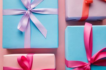 top view of colorful gift boxes with ribbons on pink background