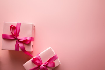 top view of gift boxes with satin ribbons on pink background