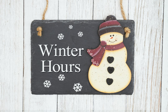 Winter Hours hanging chalkboard sign with a snowman