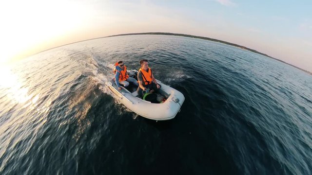 Rubber boat is sailing along the river with two men in it