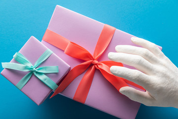 cropped view of painted hand near violet gift boxes on blue background