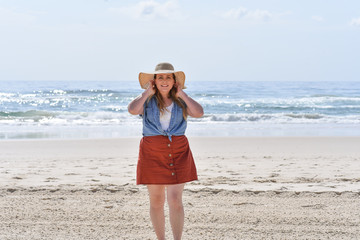 young woman at the beach wearing a big sun hat in Australia