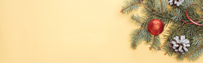 top view of christmas tree branch with bauble on yellow background, panoramic shot