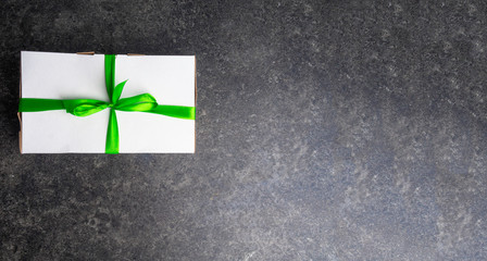 white gift box with green ribbon and bow on grey background. Beautiful greeting card . Happy Mothers day or Happy birthday concept. Happy New Year
