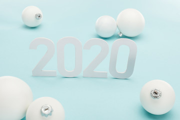white 2020 numbers near Christmas baubles on light blue background